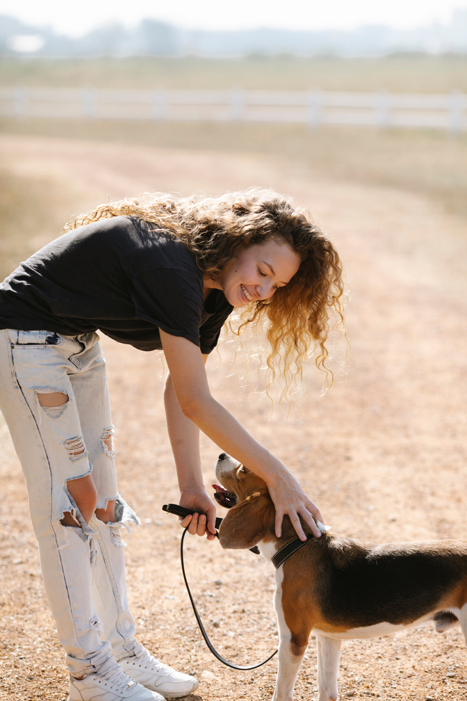 Cheerful woman petting dog on countryside road